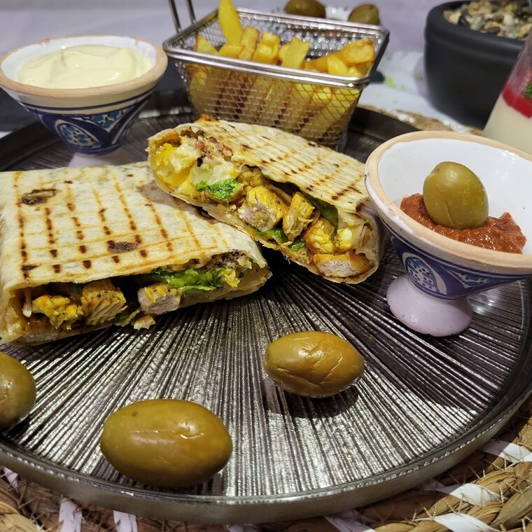 Wrap au poulet coupé en deux, servi avec des frites et des olives