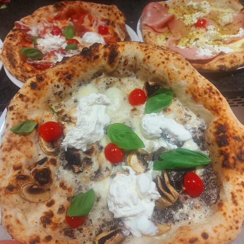 Pizza napolitaine au jambon cru, tomates et basilic, sortie du four à bois